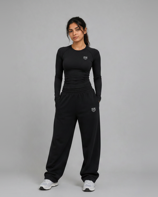 Woman wearing a black athletic outfit with logos on a gray background