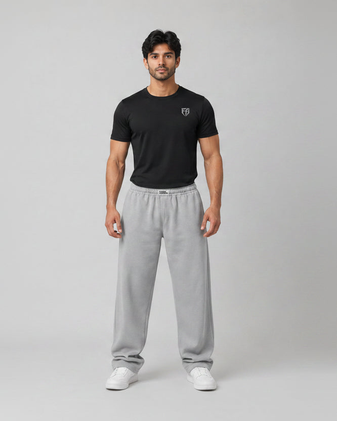 Man wearing a black t-shirt and gray sweatpants on a gray background