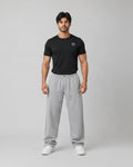 Man wearing a black t-shirt and gray sweatpants on a gray background