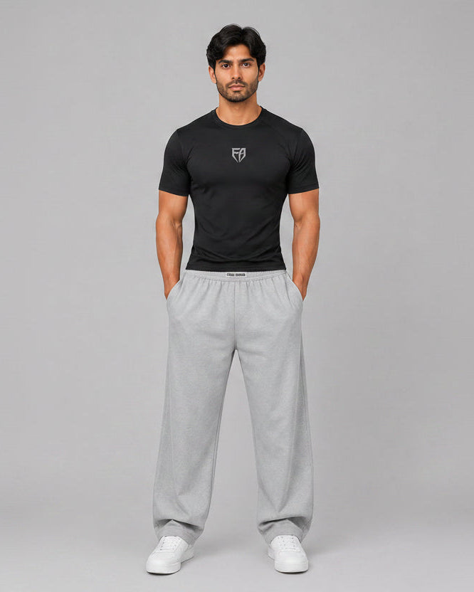 Man wearing a black t-shirt and gray sweatpants on a gray background