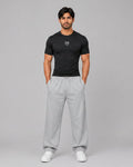 Man wearing a black t-shirt and gray sweatpants on a gray background