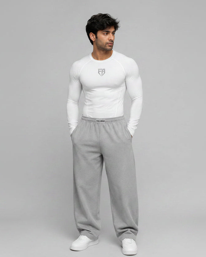 Man wearing a white long-sleeve shirt and gray sweatpants on a gray background