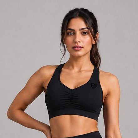 Woman wearing a black sports bra and leggings set on a gray background